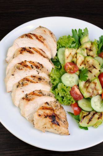 Sliced chicken over zucchini pasta and veggies