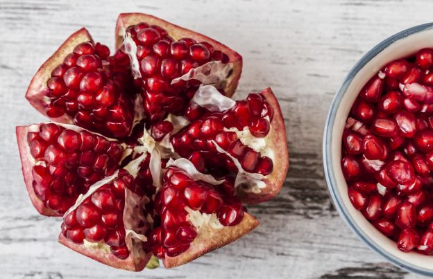 Remove pomegranate seeds using a wooden spoon