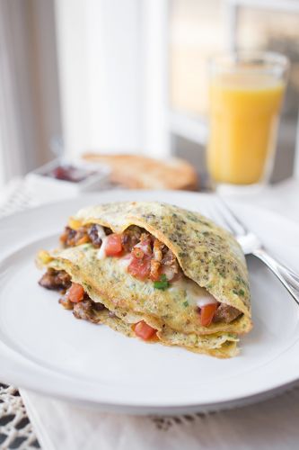 Cheesy egg “crepes” with crispy pancetta, sausage, gruyere cheese, diced tomato and chives